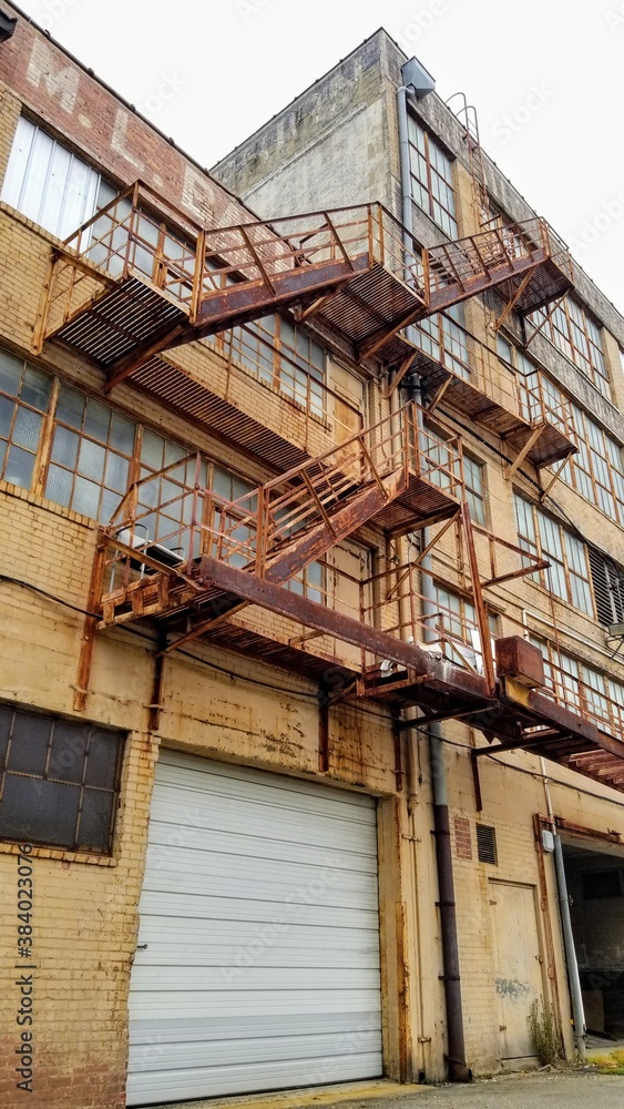 Tan building back with patinaed fire escapes and windows. (Portrait Orientation)