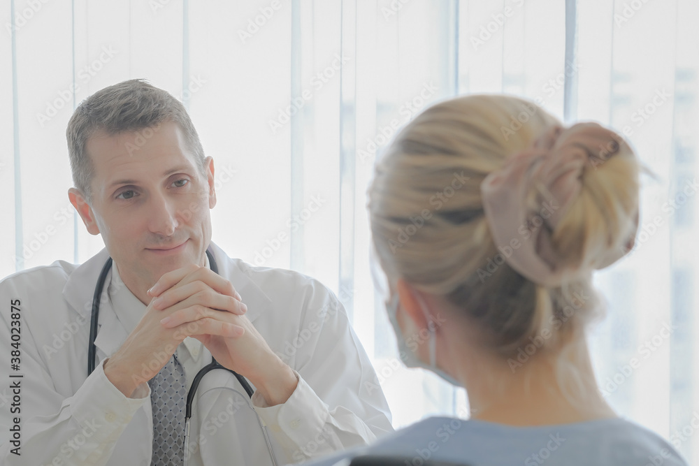 Expert doctor talking to admitted patient with face mask to follow up treatment in hospital examination room background. Expert doctor talking to admitted patient with face mask to follow up treatment in hospital examination room background.