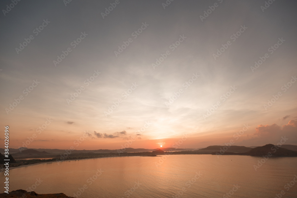 Scenic sunrise view at Merese hill, Lombok island, Indonesia.Beautiful golden sky over the sea behind mountains in background