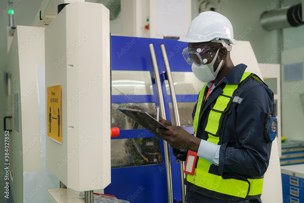 factory foreman with face mask operating with CNC machine control panel factory foreman with face mask operating with CNC machine control panel