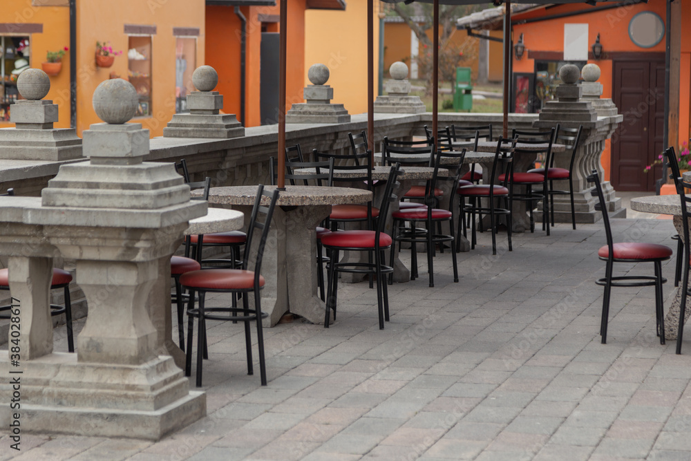 restaurant with tables and chairs with red metal seat on a stone terrace with classic design handrail, outdoor decoration