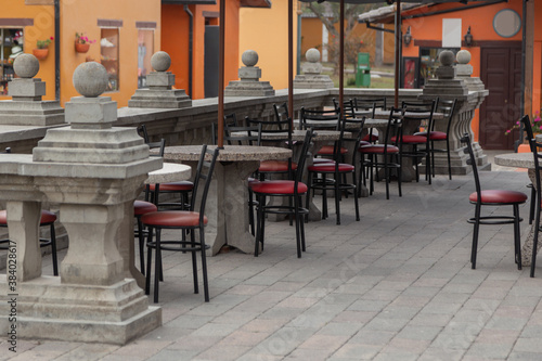 restaurant with tables and chairs with red metal seat on a stone terrace with classic design handrail  outdoor decoration