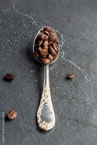 Geröstete Kaffeebohnen auf einen Silberlöffel dekoriert.