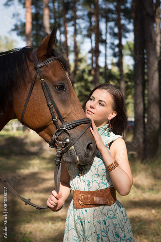 Young beautiful woman hugs her horse in the forest 