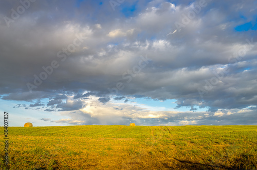 Rural landscape with clouds and harvested hay field