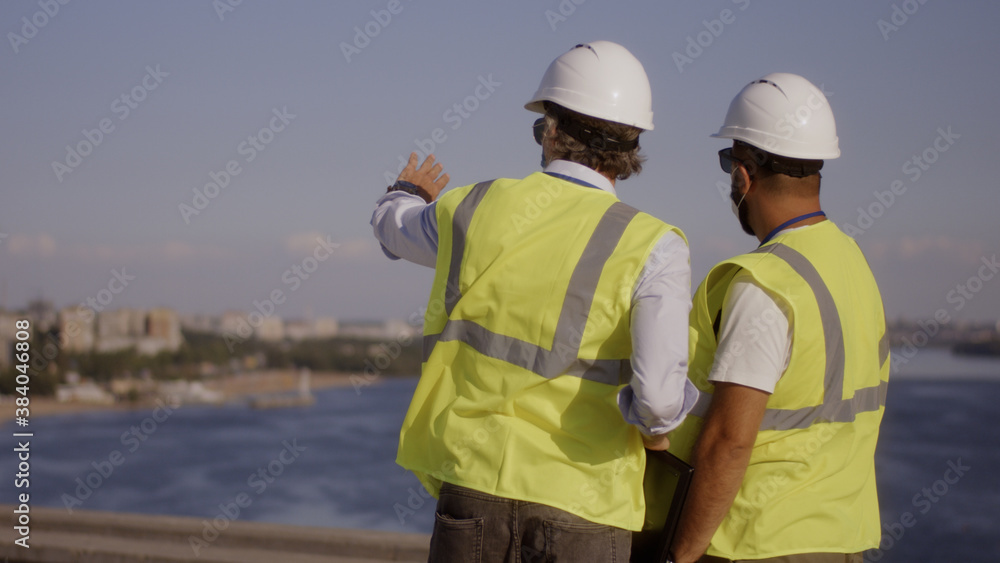 Contactors in masks talking on construction site Contactors in masks talking on construction site