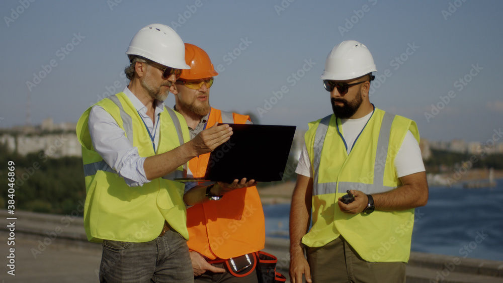 Builders using laptop on construction site Builders using laptop on construction site