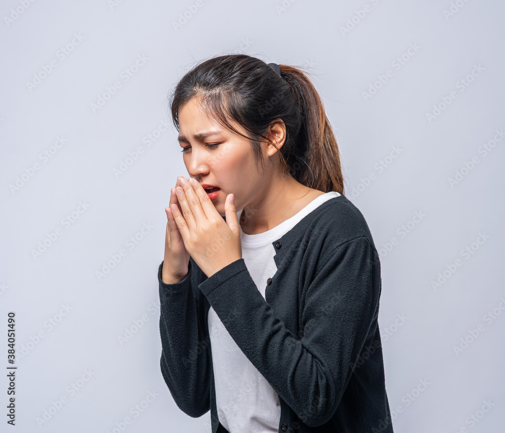 A woman coughing and covering her mouth with her hand A woman coughing and covering her mouth with her hand