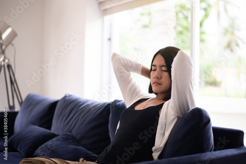 Asian woman sitting on sofa in living room with hands over head,Relaxing time