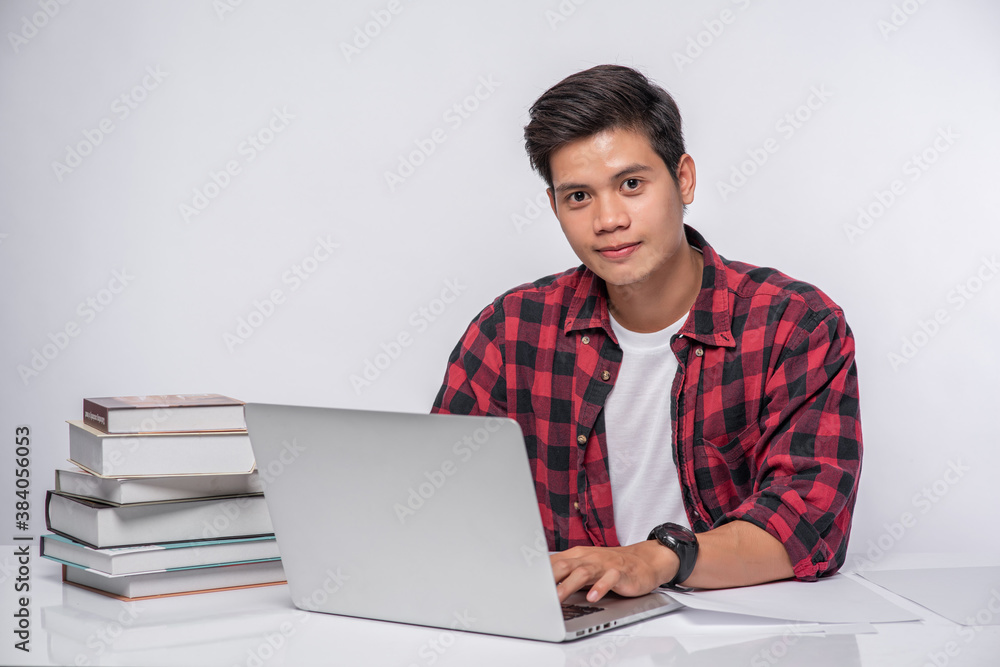 A man wearing a striped shirt uses a laptop to work. A man wearing a striped shirt uses a laptop to work.
