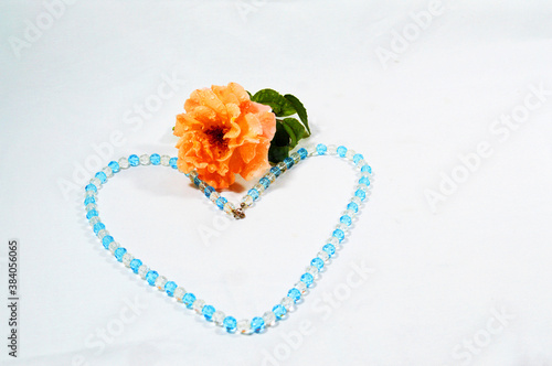 Old rose flower with leaves surrounded by crystal necklage in heart form on white background  3 photo