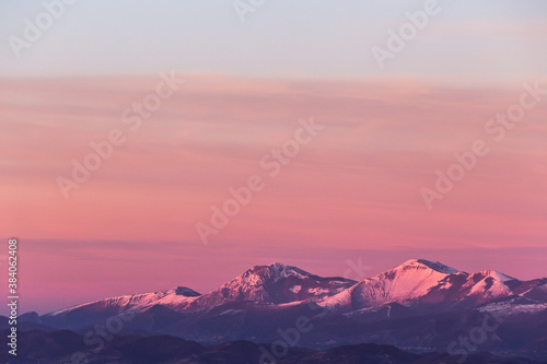 Mountain top covered by snow with a beautiful orange sky on the background © Massimo