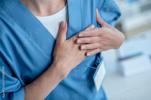 Close up of a person in blue clothes pressing hands to the heart
