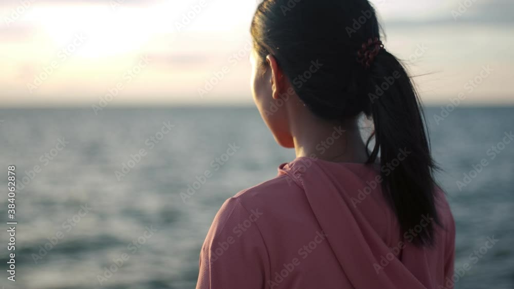 Woman runner standing seaside taking a break from exercising admiring the view of the beach sunset. Woman runner standing seaside taking a break from exercising admiring the view of the beach sunset.