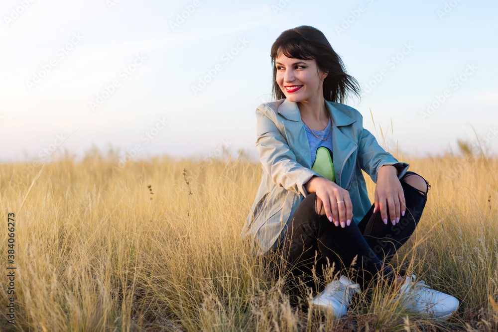 Brunette woman sitting in yellow steppe grass. Brunette woman sitting in yellow steppe grass.