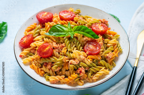 Fusilli - classic italian pasta from durum wheat with chicken meat, tomatoes cherry, basil in tomato sauce in white bowl on blue wooden table Mediterranean cuisine Top view Flat lay