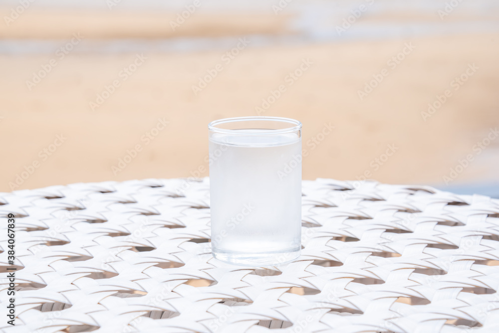 A glass of drinking water on white table next to the beach A glass of drinking water on white table next to the beach
