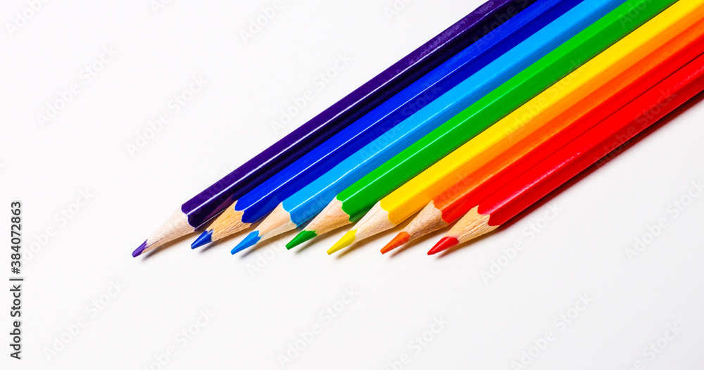 On a white background, color pencils from the side close-up stacked in the colors of the rainbow On a white background, color pencils from the side close-up stacked in the colors of the rainbow