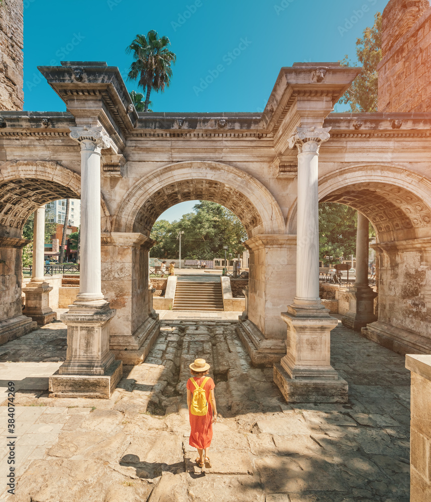 Naklejka premium Happy female tourist traveler discover interesting places and popular attractions and walks in the old city of Antalya, Turkey. The famous Roman gate of Hadrian