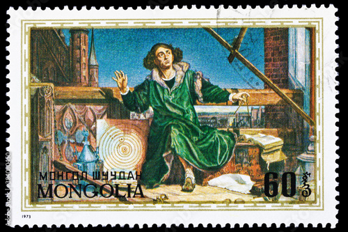 A postage stamp printed in Mongolia shows Nikolai Copernicus sitting in a workshop with tools, circa 1973. Macro photography. Complete clipping.