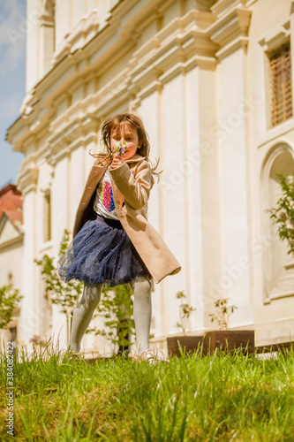 Young beautiful child girl holding flowers and dancing outdoors. © zwiebackesser