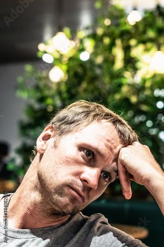 Front closeup vertical portrait Young serious pensive man thinking, hand props forehead holds head, look dismissively sad mood facial expressions gesture. Motivation people life crisis problem solving photo