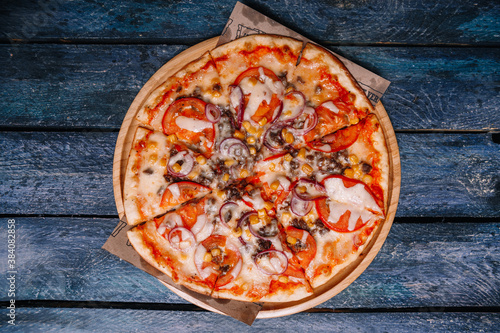 .Pizza with corn, meat and tomatoes on a background of boards
