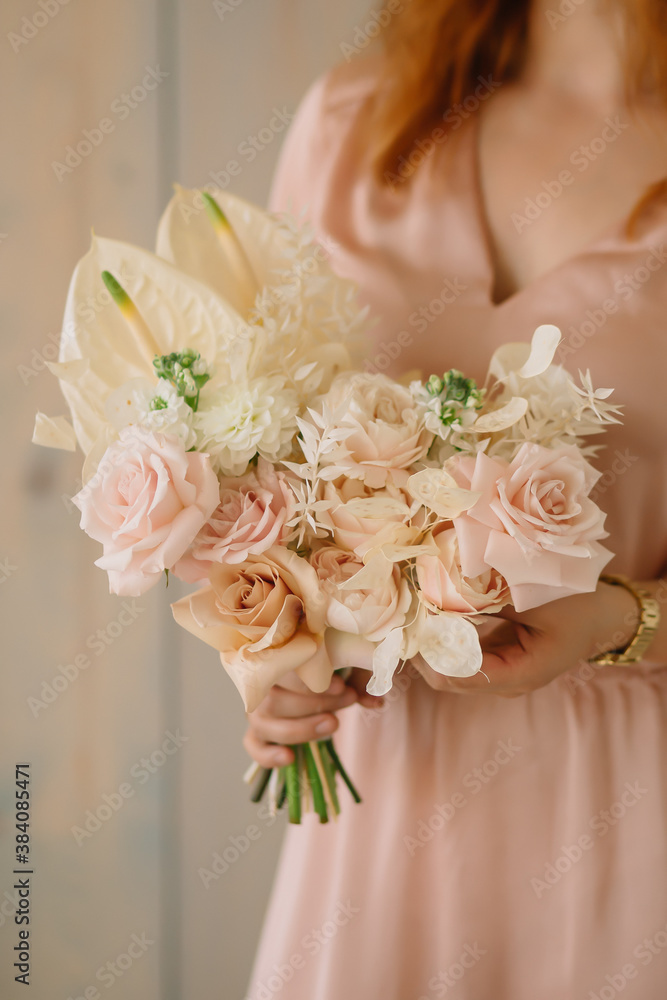 Naklejka premium young woman florist in a pink dress with red hair holds a wedding bouquet of flowers roses