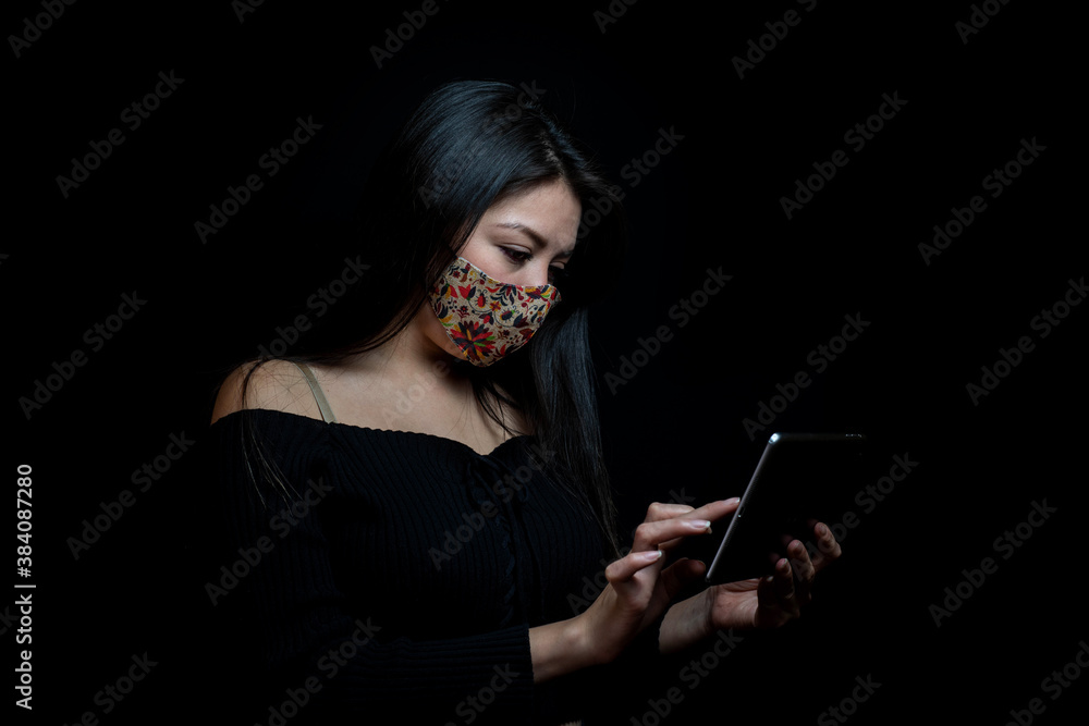 young man with mask looking at his tablet or cell phone young man with mask looking at his tablet or cell phone