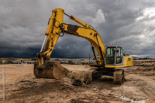 Excavator at a construction site surrounded by dramatic clouds