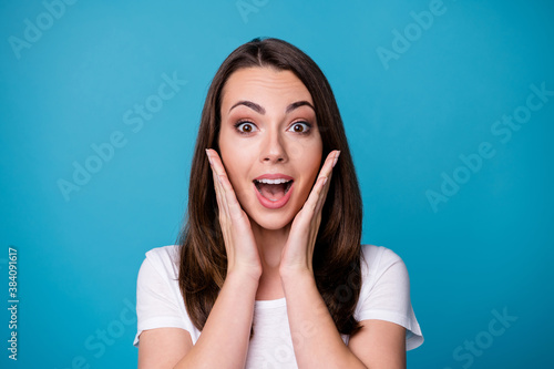Closeup photo of attractive pretty funny lady good mood charming cute straight hairstyle arms on cheeks shocked amazing news wear casual white t-shirt isolated blue color background