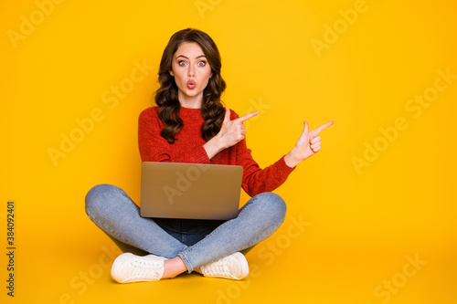 Photo of attractive shocked lady sit floor legs crossed work computer remote worker education home direct fingers empty space wear casual outfit isolated yellow color background