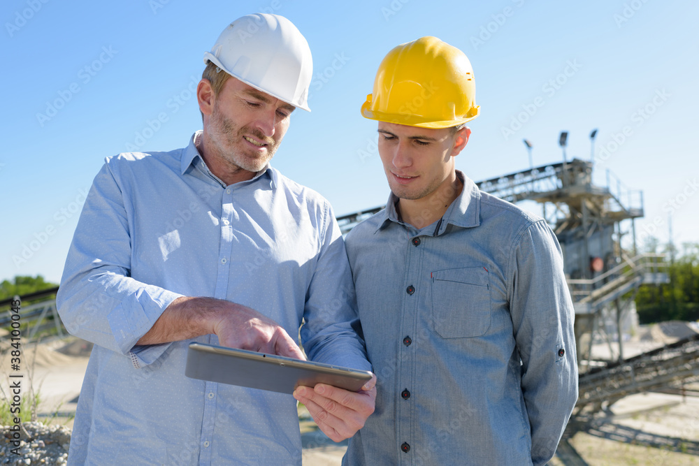 two builders outdoors looking at tablet two builders outdoors looking at tablet