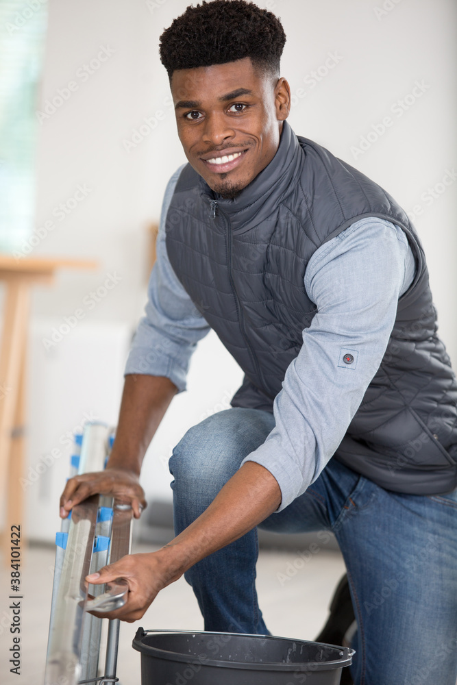 young male worker standing next to a ladder young male worker standing next to a ladder