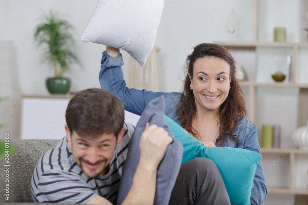 couple having fun fighting pillows in the room couple having fun fighting pillows in the room