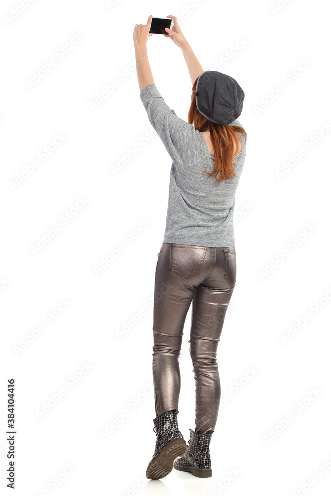 Young Casual Woman Is Holding Up Telephne And Taking A Photo. Rear View. Young Casual Woman Is Holding Up Telephne And Taking A Photo. Rear View.