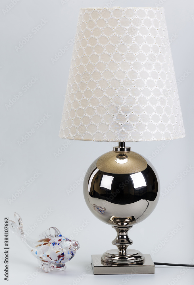 beautiful metal table lamp with a figurine small fish on a bedside table
