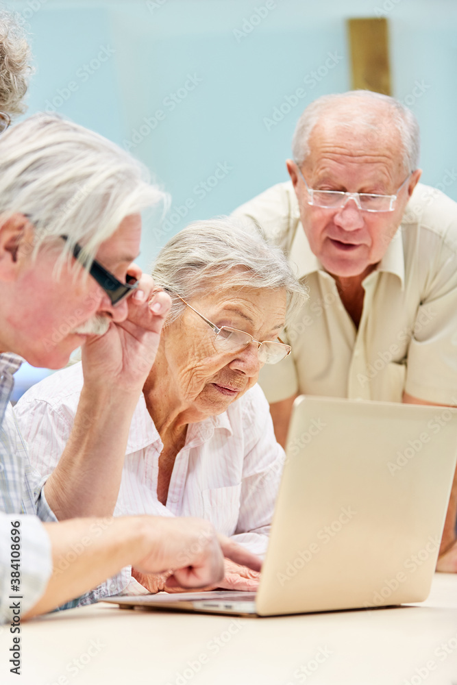 Drei Senioren arbeiten neugierig am Laptop PC