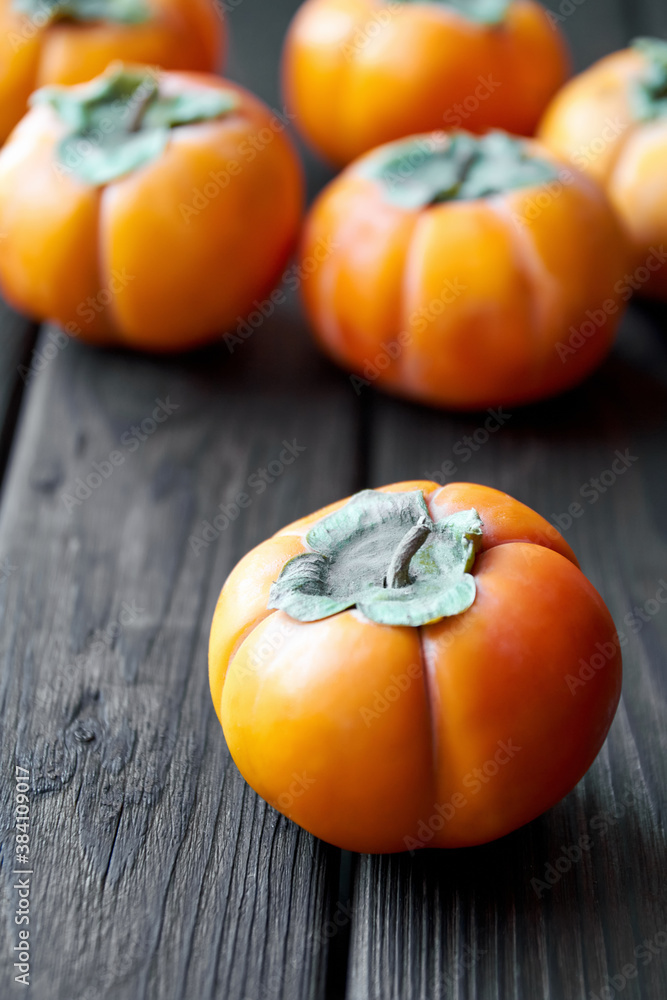 Ripe fresh persimmon on brown wooden rustic background. Close-up, selective focus Ripe fresh persimmon on brown wooden rustic background. Close-up, selective focus
