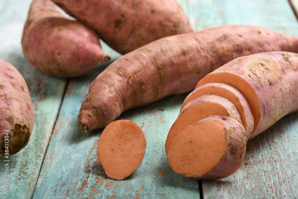 raw sweet potatoes on a wooden table raw sweet potatoes on a wooden table