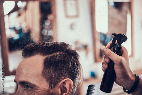 Hairdresser sprays water on client hair.