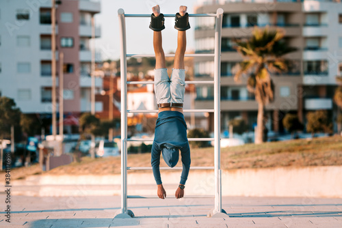 Fototapeta Man hanging upside down on the horizontal bar in anti gravity or inversion boots
