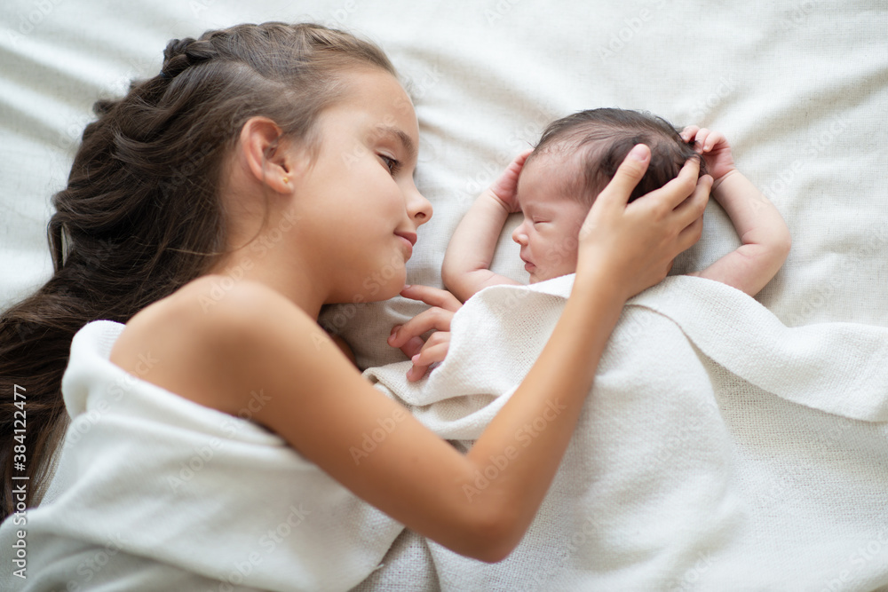 Little girl sleeps with her new born baby sister at home. Cute children's portrait Little girl sleeps with her new born baby sister at home. Cute children's portrait