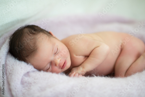 New born baby girl sleeps at home and smiling in a dream. Cute little kid's portrait