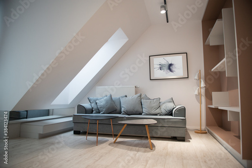 Modern design home interior of living room in mansard with sofa and elegant accessories. Stylish home decor with mock up abstract paintings on the wall.
