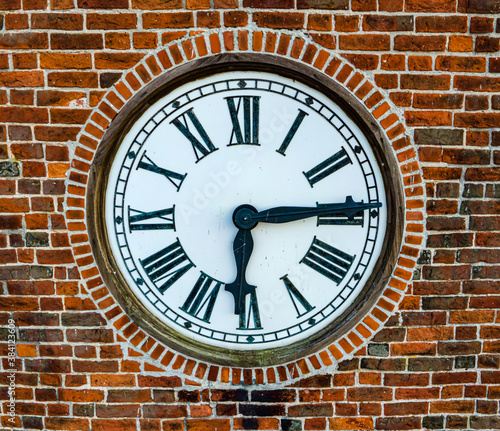 Old clock in a church tower with bricks around it. Close up.