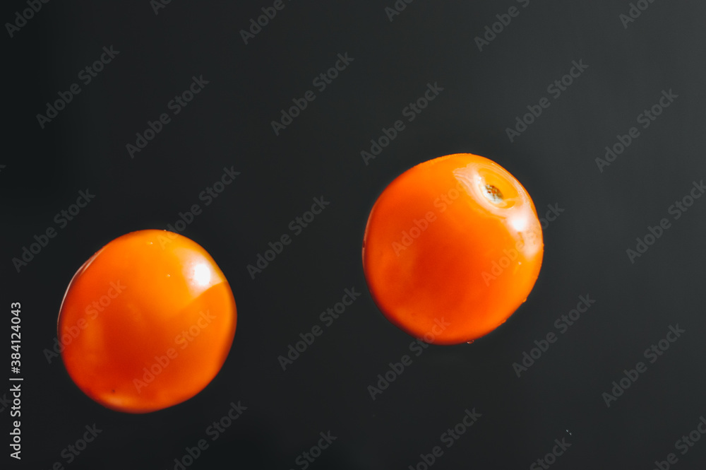 Naklejka Falling tomatoes isolated on a black background, freeze in motion