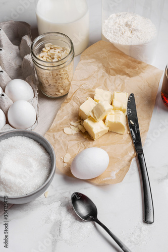 Ingredients and tools for home baking on a culinary background. Eggs, flour, milk, sugar, butter, almond flakes, syrup on the kitchen table. Concept of preparation for baking. Homemade pastry. Cooking