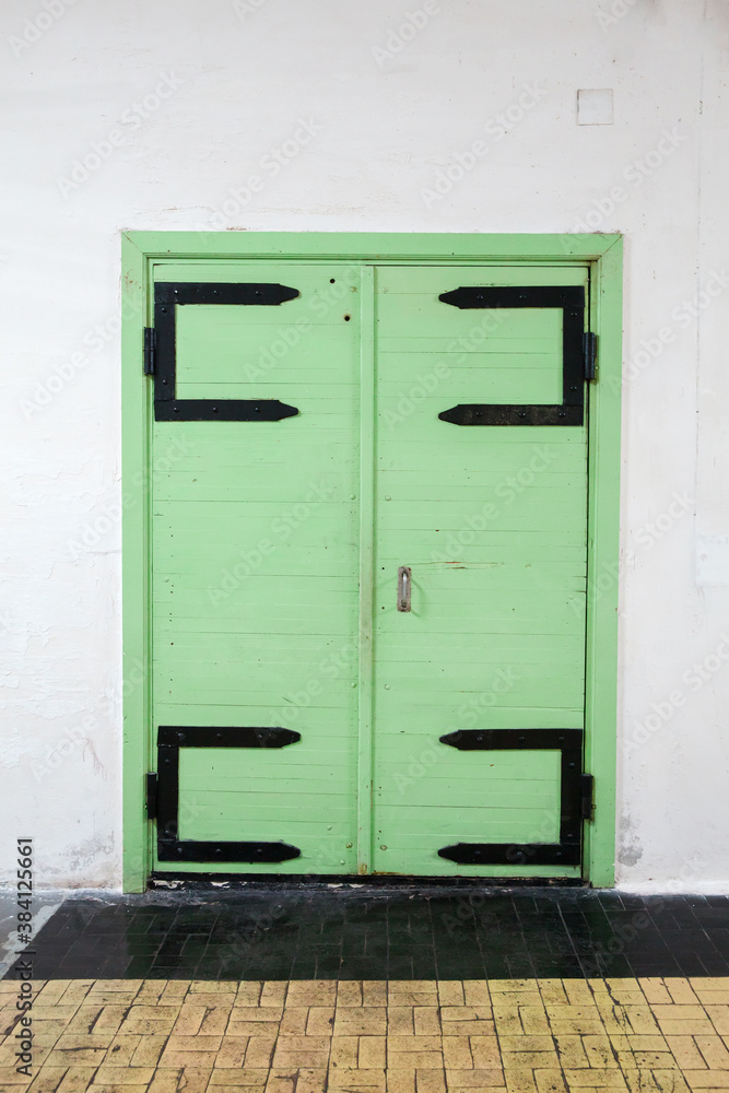 Old green wooden door in white wall, background photo