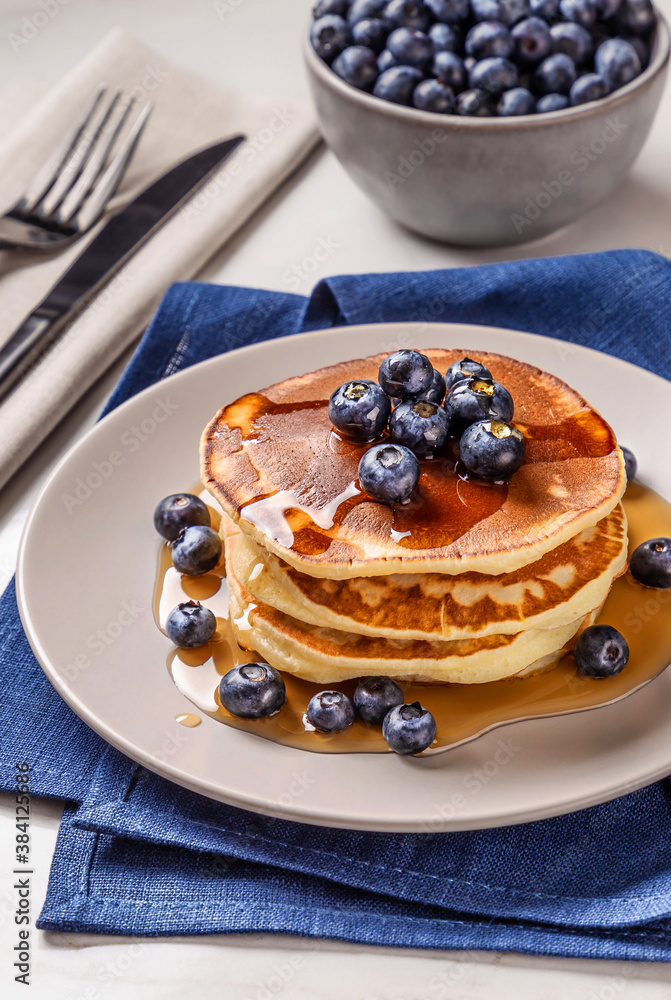 American breakfast. Stack of homemade american pancakes with fresh berry and pouring maple syrup on a white background. Fresh blueberries. Food photo. Breakfast photo. Recipe. Fluffy. Close up view American breakfast. Stack of homemade american pancakes with fresh berry and pouring maple syrup on a white background. Fresh blueberries. Food photo. Breakfast photo. Recipe. Fluffy. Close up view